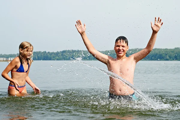 Mädchen und Junge bespritzen sich am Strand mit Wasser — Stockfoto