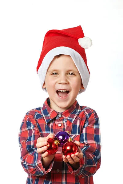 Kleiner Junge in roter Weihnachtsmütze mit glänzenden Weihnachtskugeln — Stockfoto