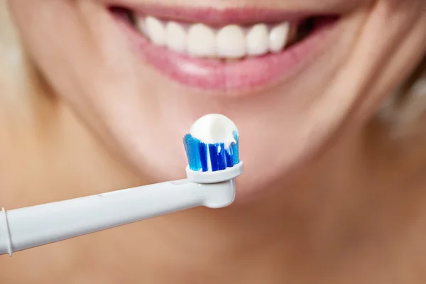 Kobieta szczotkowanie zębów elektryczne szczoteczki do zębów z pasty do zębów — Zdjęcie stockowe