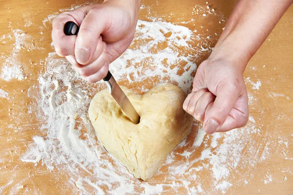 Nervous woman pierces heart of dough with kitchen knife — Stock Photo, Image