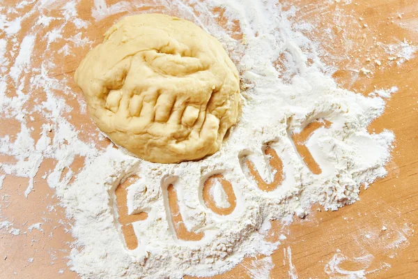 Funny knead dough and flour on wooden table with text — Stock Photo, Image