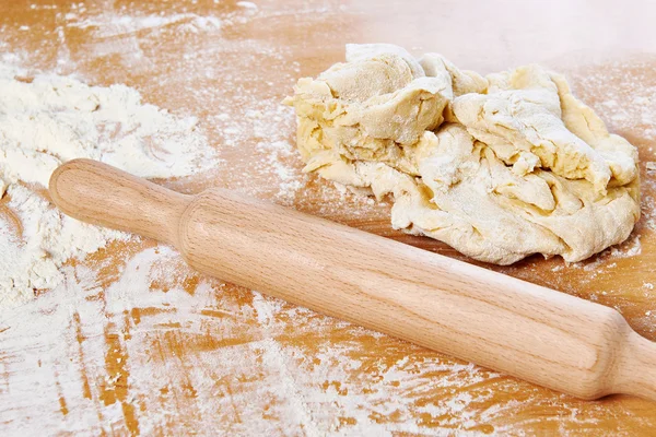 Rolling pin and dough on kitchen table — Stock Photo, Image
