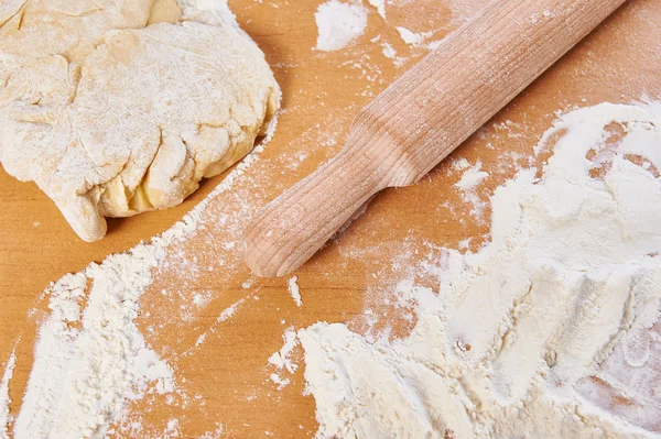 Wooden rolling pin and dough on kitchen table — Stock Photo, Image
