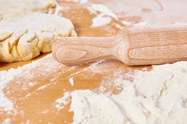 Wooden rolling pin and dough on kitchen table — Stock Photo, Image