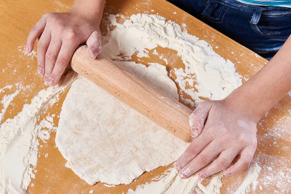 Девушка готовит тесто со скалкой на кухонном столе — стоковое фото