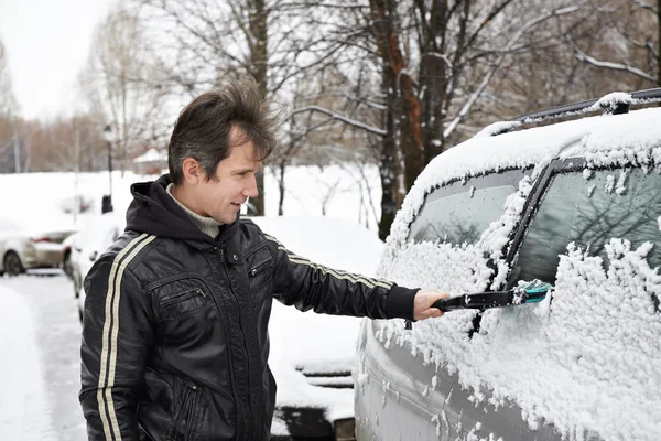 Chauffeur avec brosse nettoie la voiture de la neige — Photo