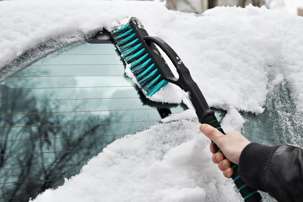 Man rengör bil från snö med borste — Stockfoto