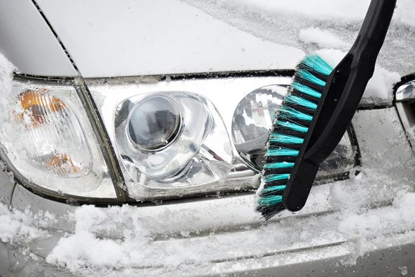 Man reinigt auto van sneeuw met borstel — Stockfoto