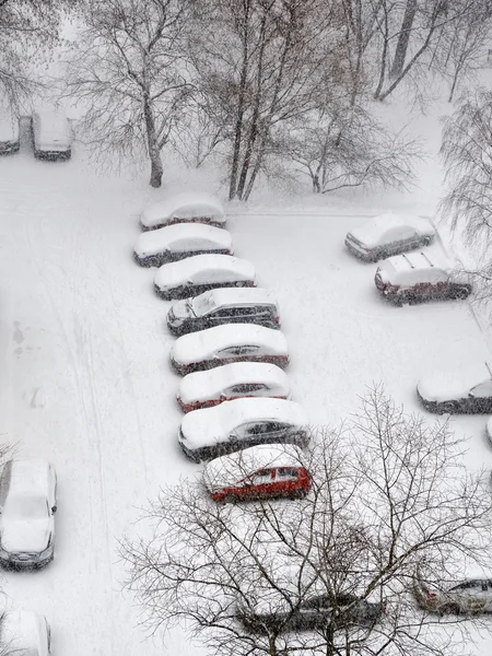 Snöfall i staden och bilar på parkering — Stockfoto