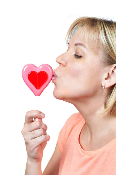 Happy girl kissing heart shaped lollipop — Stock Photo, Image