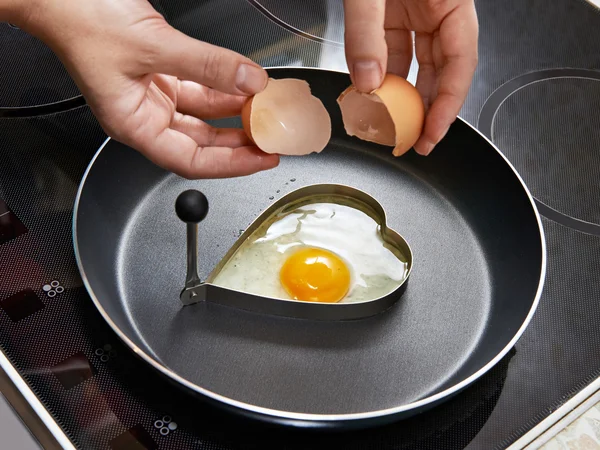 Woman preparing fried eggs in heart form — Stock Photo, Image