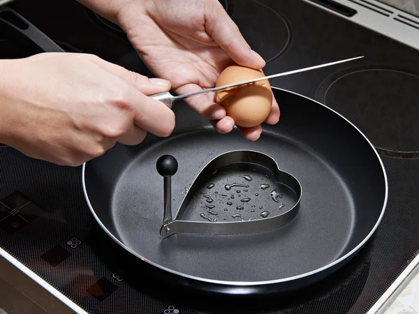Женщина готовит яичницу в форме сердца — стоковое фото