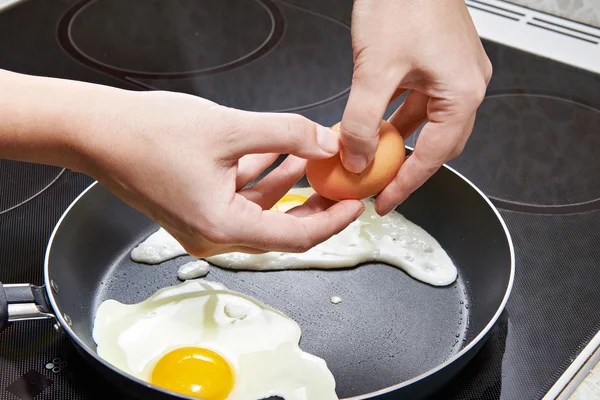 Femme casse un oeuf dans des œufs frits — Photo