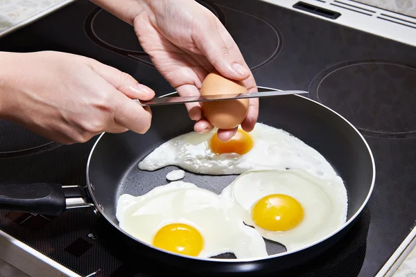 Mujer rompe un huevo en huevos fritos — Foto de Stock