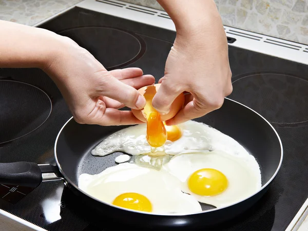 Жінка розбиває яйце в смажених яйцях — стокове фото