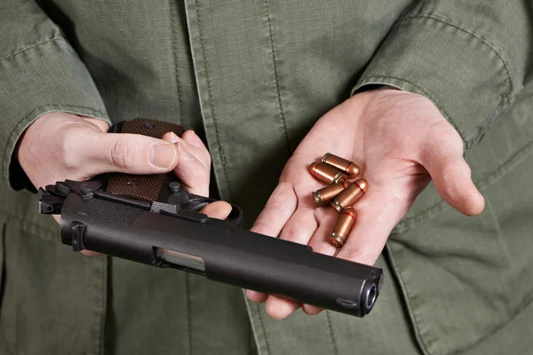 Soldier holding gun Colt and cartridges — Stock Photo, Image