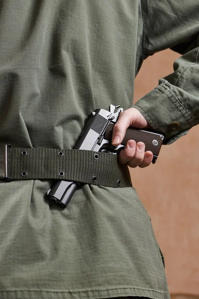 Soldier in uniform holding gun in his belt — Stock Photo, Image