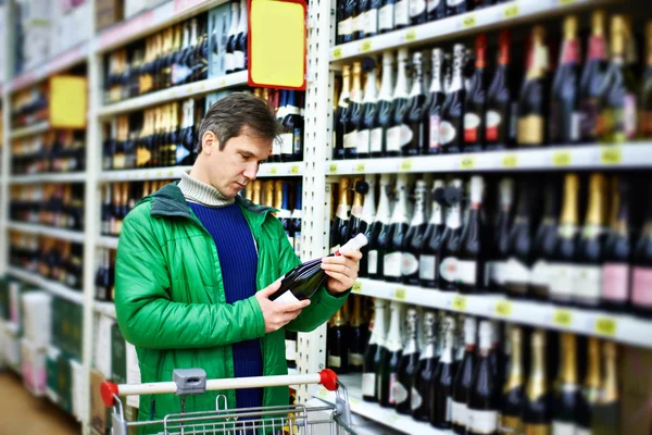 Człowiek wybiera wina w supermarkecie — Zdjęcie stockowe