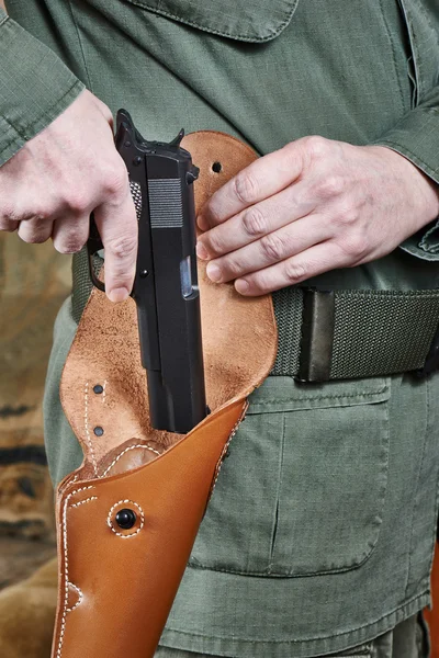 Soldier puts gun in holster — Stock Photo, Image