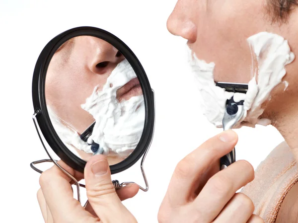 Man looks in mirror and shaving — Stock Photo, Image