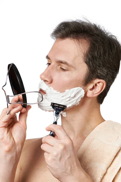 Man looks in mirror and shaving — Stock Photo, Image