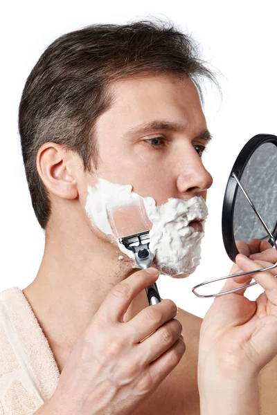 Man looks in mirror and shaving — Stock Photo, Image