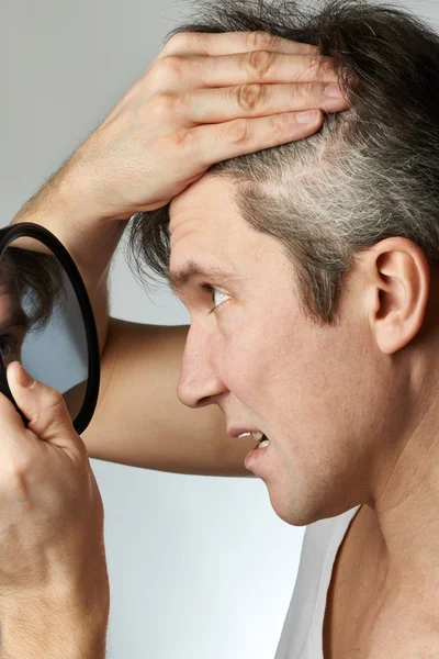 Man with mirror looking at his hair — Stock Photo, Image