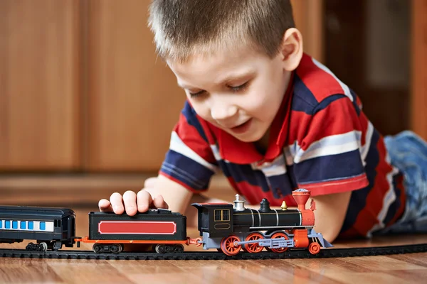 Маленький хлопчик грає з залізницею, що лежить на підлозі — стокове фото