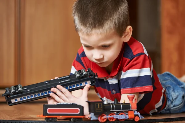 Menino brincando com a ferrovia deitada no chão — Fotografia de Stock