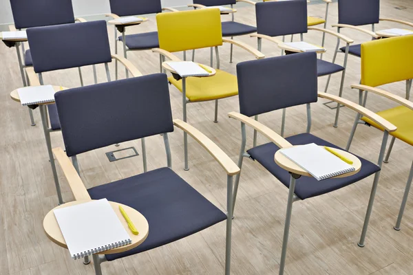 Chairs with notepads in empty classroom — Stock Photo, Image