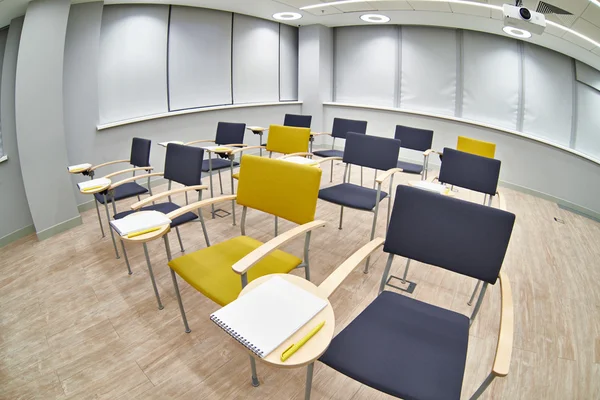 Chaises avec bloc-notes dans une salle de classe vide — Photo