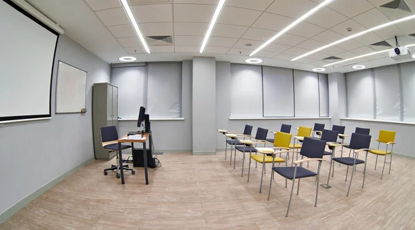 Cadeiras com blocos de notas em uma sala de aula vazia — Fotografia de Stock