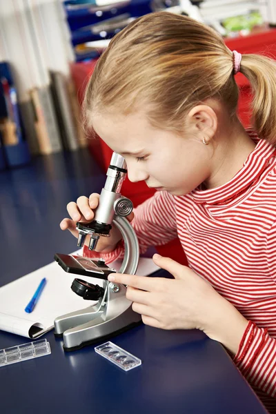 Fille regardant à travers un microscope — Photo