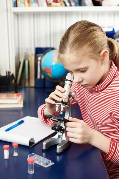 Fille regardant à travers un microscope — Photo