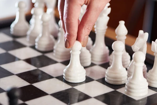 Hand with white pawn on chessboard — Stock Photo, Image