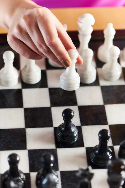Χέρι με λευκό πιόνι πάνω από την σκακιέρα — Φωτογραφία Αρχείου