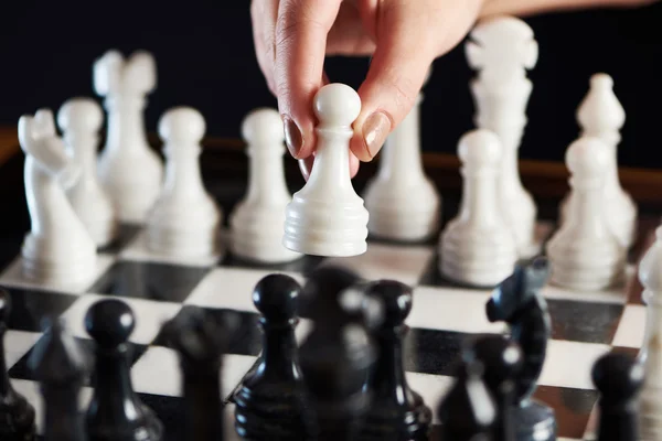 Hand with white pawn over chessboard — Stock Photo, Image