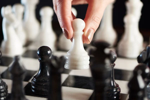 Mano con peón blanco sobre tablero de ajedrez — Foto de Stock