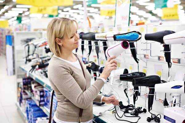 Woman chooses hairdryer in store — Stock Photo, Image