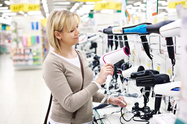 Woman chooses hairdryer in store — Stock Photo, Image