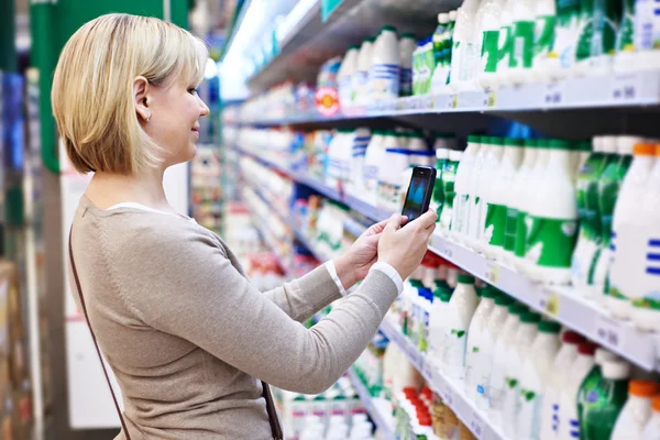 Mujer fotografiando con etiqueta de smartphone de productos lácteos —  Fotos de Stock