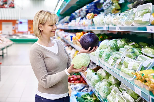 Woman buys a red and white cabbage in store — Stock Photo, Image