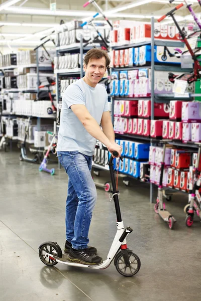 Hombre tratando de scooter en tienda de deportes —  Fotos de Stock