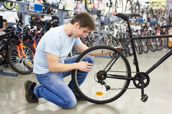 Man controles fiets alvorens te kopen in sportzaak — Stockfoto