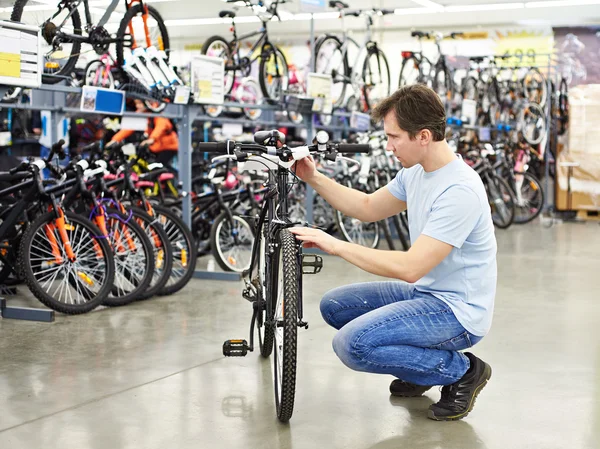 Homem verifica bicicleta antes de comprar na loja de esportes Imagens De Bancos De Imagens Sem Royalties