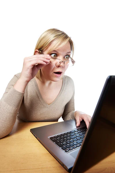 Frightened woman with glasses looking at a laptop — Stock Photo, Image