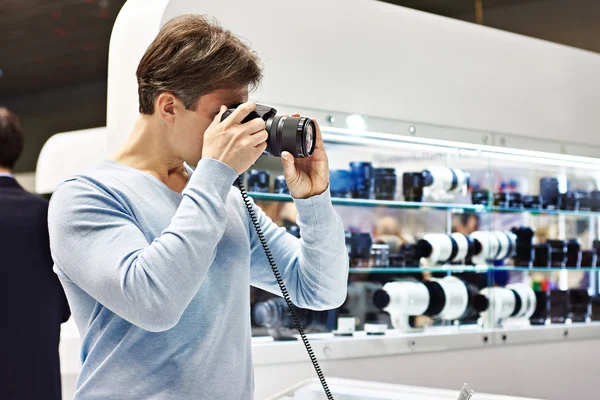 Homme photographe teste appareil photo reflex numérique dans la boutique — Photo