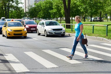 Woman crossing street at pedestrian crossing clipart
