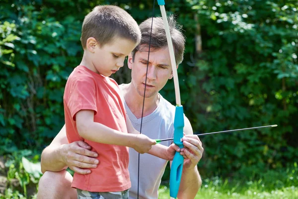 Father is learning his son to shoot from bow — Stock Photo, Image