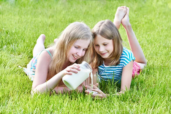 Two girls pours milk in sunny meadow — Stock Photo, Image